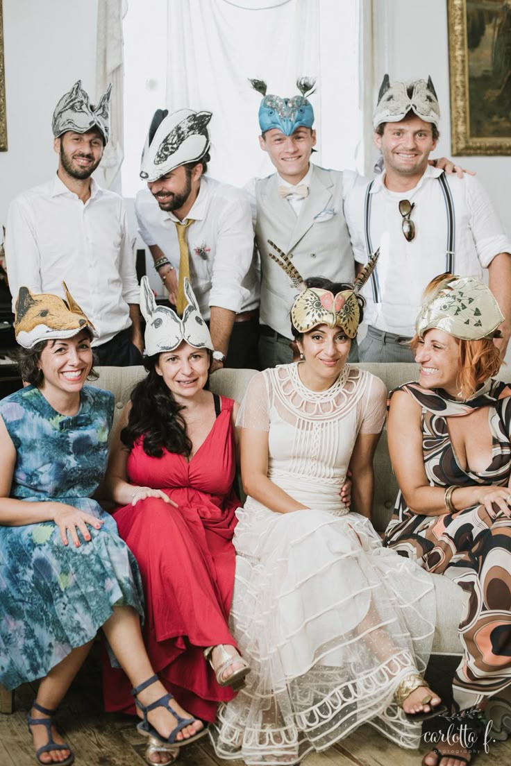 This may contain: a group of people sitting on top of a couch wearing paper hats and dresses in front of a window