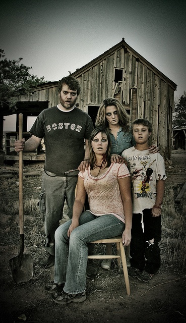 This may contain: a family poses for a photo in front of an old barn