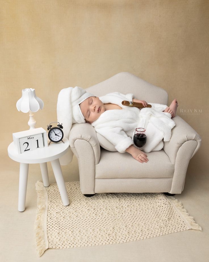This may contain: a baby is laying in a chair with a glass of wine and an alarm clock