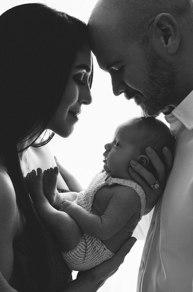 This may contain: a man and woman holding a baby in their arms