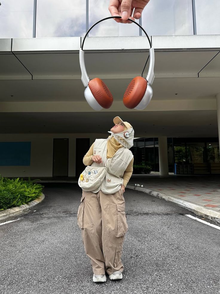 This may contain: a person holding an object in front of their head with two balls attached to it
