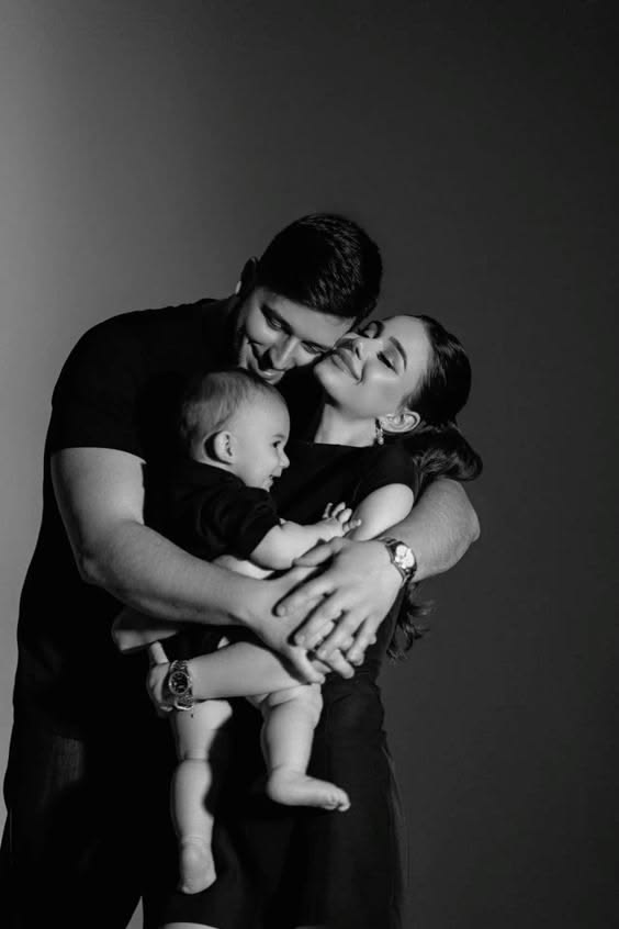 This may contain: a man and woman holding a baby in their arms