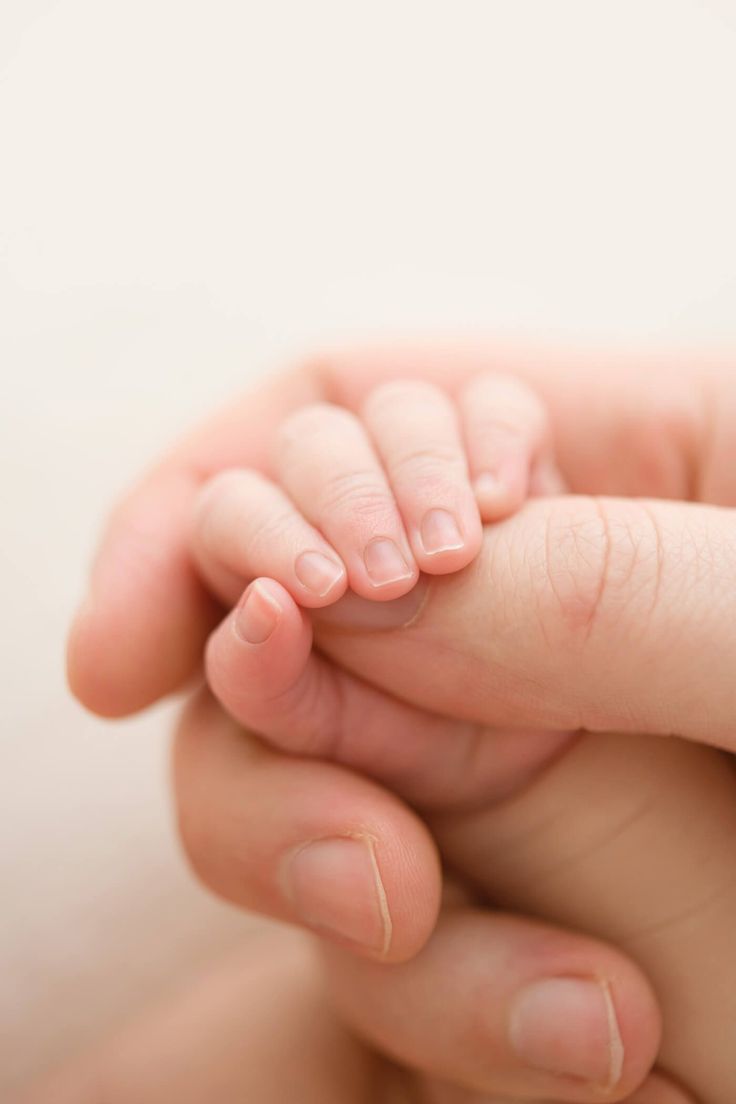 This may contain: a close up of a person holding a small baby's hand in their left hand