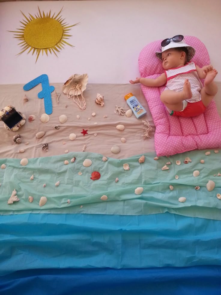 This may contain: a baby laying on top of a pink chair next to an ocean themed wallpaper