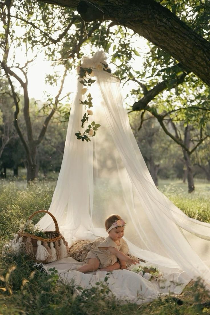 This may contain: a woman sitting in the grass under a canopy