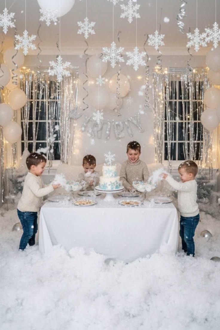 This may contain: four children standing around a table with cake and balloons in the air, surrounded by snowflakes