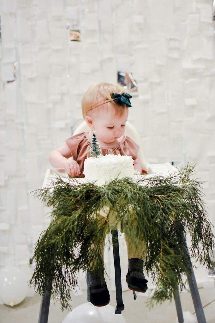 This may contain: a baby is sitting in a high chair with greenery on it's legs