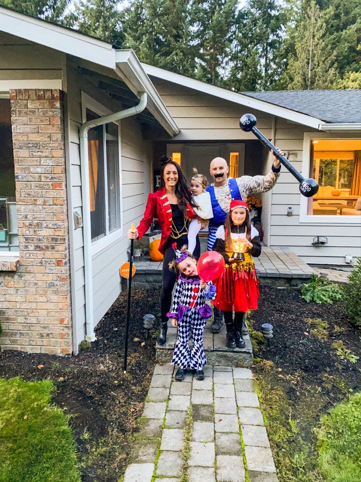 This may contain: a group of people standing in front of a house with halloween decorations on the lawn