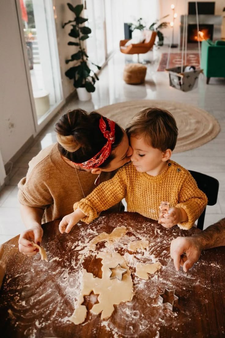 This may contain: a woman and child making cookies on a table